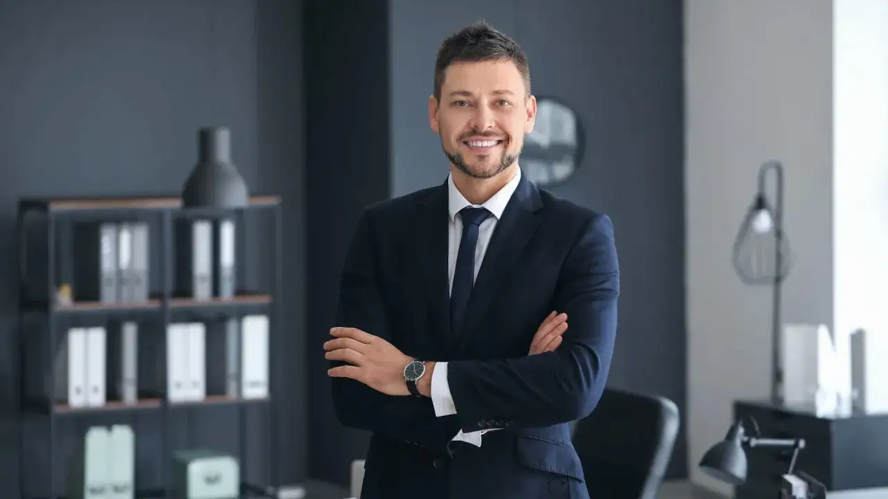 Uśmiechnięty mężczyzna w garniturze, który może być inspiracją, jak zostać agentem nieruchomości.